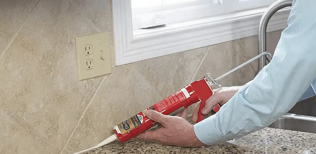 Handyman applying caulk along a kitchen backsplash and countertop seam in San Jose, CA