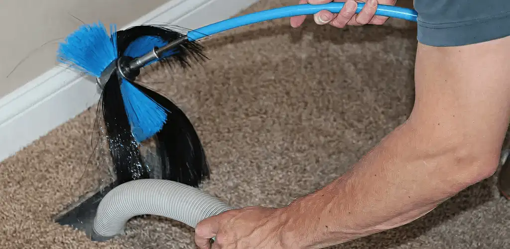 Dryer vent cleaning technician brushing lint from a vent line in San Jose, CA
