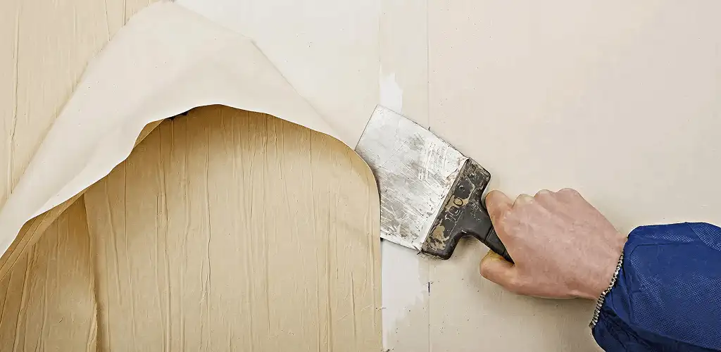 Handyman removing wallpaper with a scraper for wall preparation in San Jose, CA
