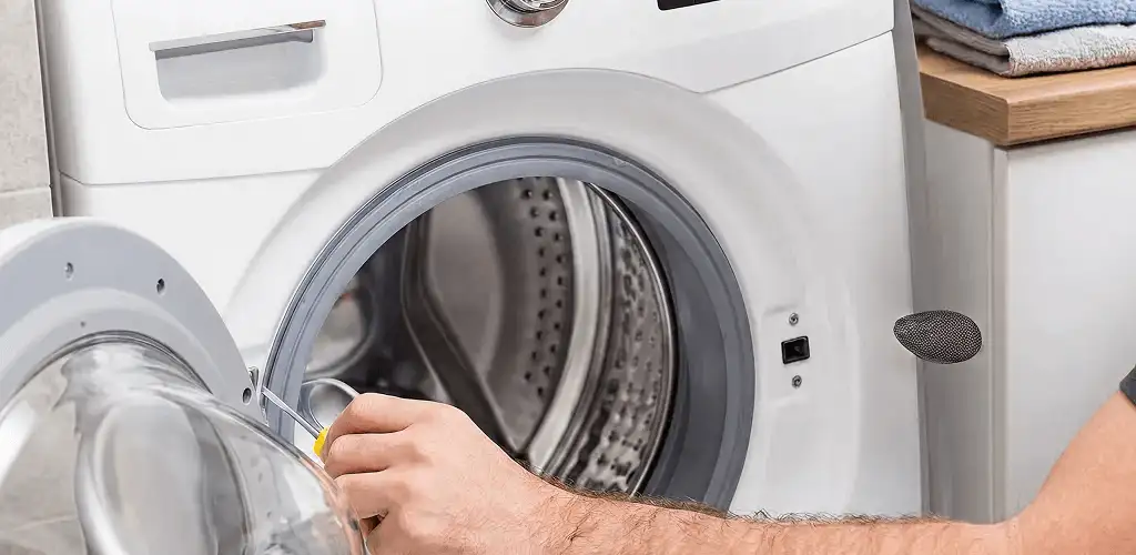 Handyman repairing a front-load washing machine and inspecting the drum in San Jose, CA