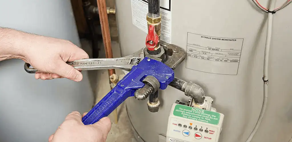 Water heater repair technician tightening the shutoff valve and supply line in San Jose, CA